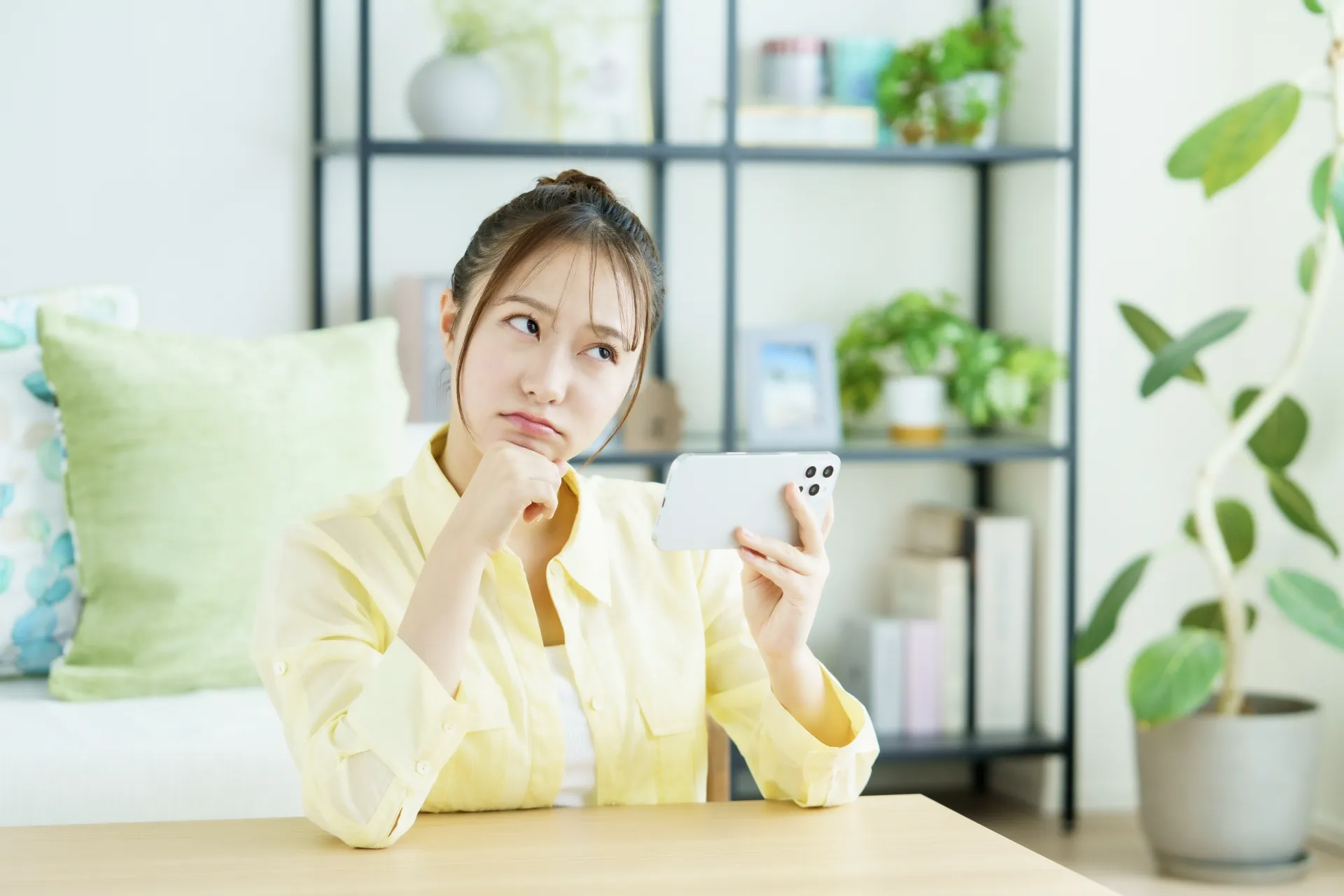 スマホを見ながら動画配信サービス選びに悩む女性